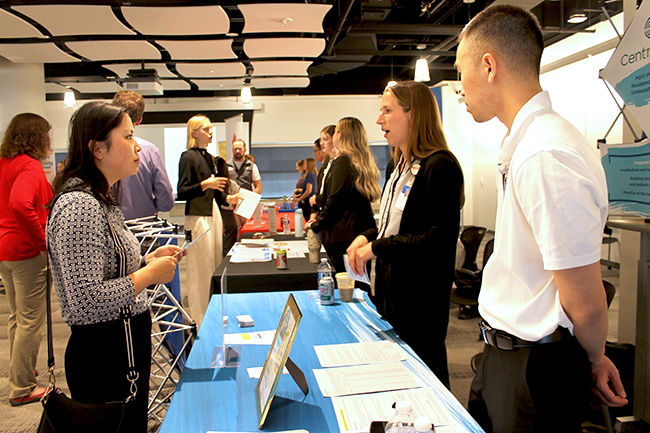 A student chats with representatives at a booth at the annual Pharmacy Career Fair