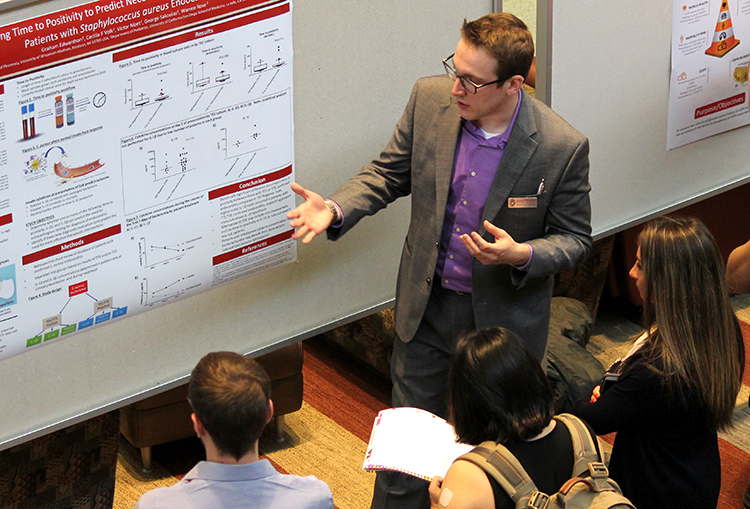 PharmD student Graham Edwards discusses his research at a poster session