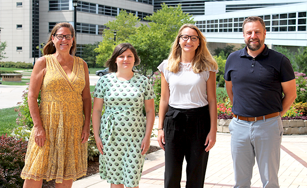 Student Service team members stand outside Rennebohm Hall on a sunny day