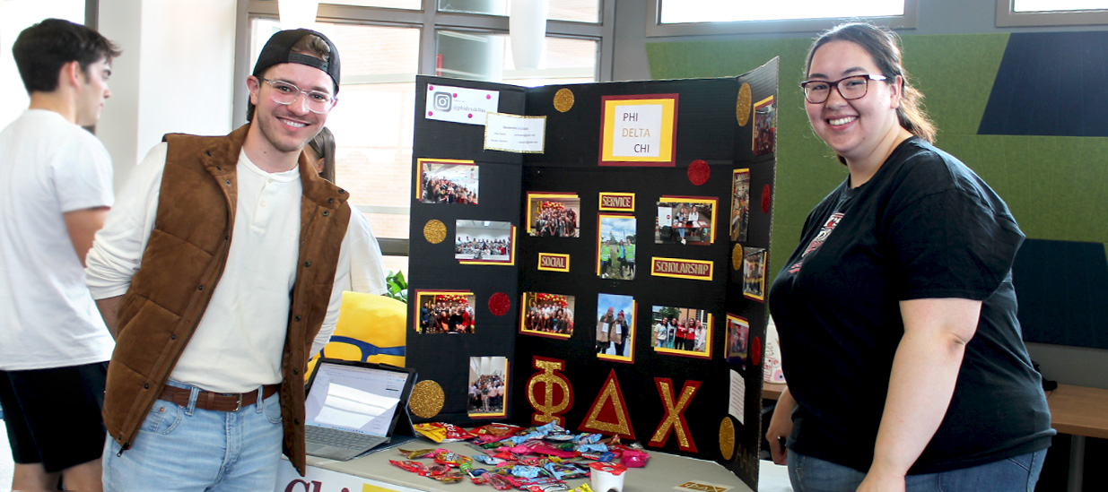 Two Rho Chi representatives pose together in front of their booth at the Student Org Fair at PharmD Orientation